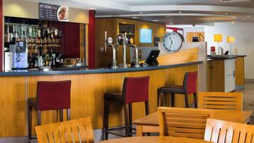 Una zona de bar con múltiples grifos, un reloj y muebles de madera.