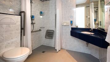 A bathroom with a toilet, shower, and sink.