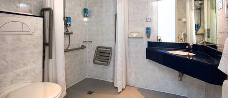 A bathroom with a toilet, shower, and sink.