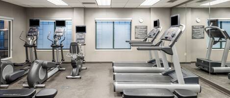A gym with treadmills, elliptical machines, and weight benches.