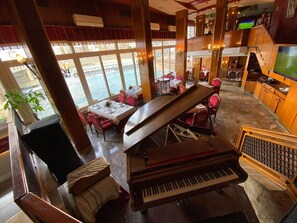 A spacious lobby with a grand piano, comfortable seating, and large windows offering a view of the sea.