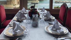 A dining table set for a meal with a view of a bridge and buildings across the water. - San Giovanni Stanly Hotel & Restaurant (Alexandria)