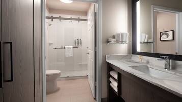 A modern bathroom with a glass shower enclosure, a white toilet, and a vanity with a mirror.