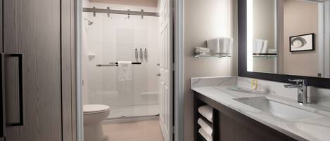 A modern bathroom with a glass shower enclosure, a toilet, a sink with a mirror, and a towel rack.