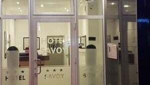 A hotel entrance with a revolving door, glass doors, and a red carpet. - Hotel Savoy Bonn (Bonn)