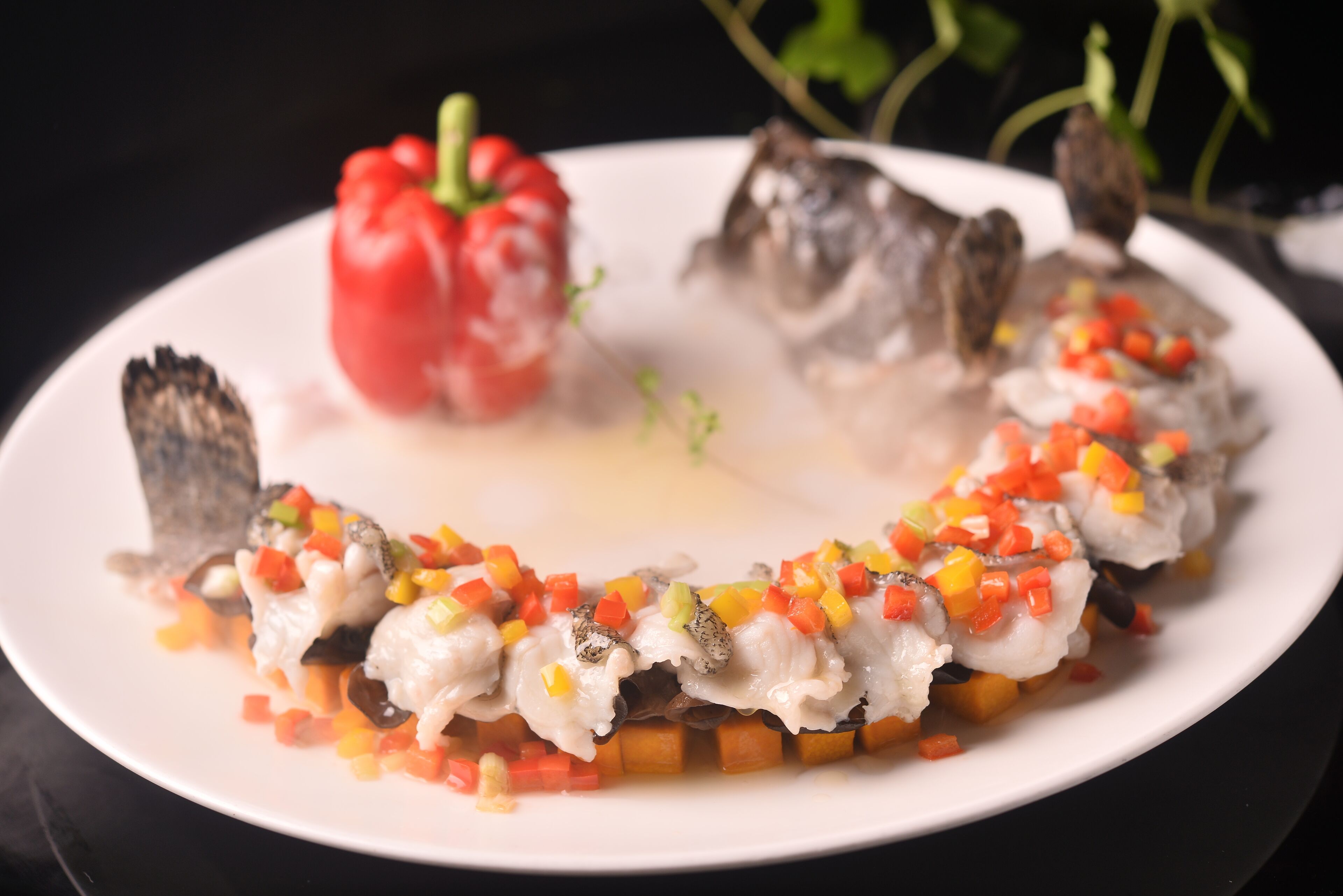 A plate of food with a red bell pepper, fish, and diced vegetables.