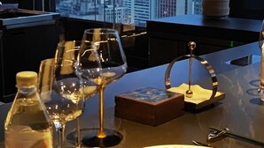 Una mesa de comedor dispuesta con copas de vino, una botella de agua y una servilleta enrollada.