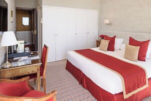 Een hotelkamer met een bed, een bureau, een stoel, een kledingkast en een nachtkastje met een lamp.