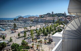 Un puerto deportivo con barcos, un paisaje urbano con edificios históricos y una vista despejada del mar.