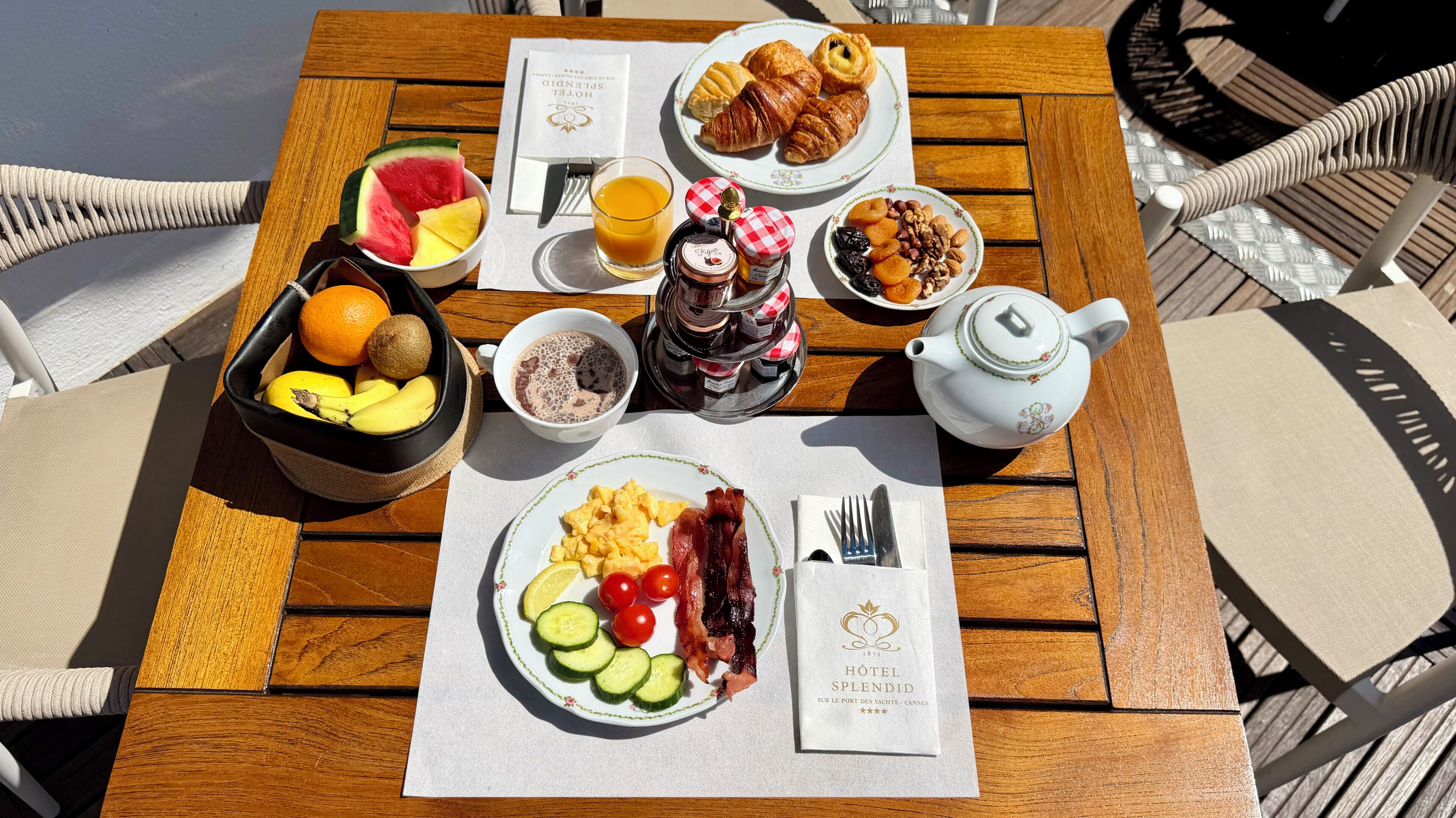 Et morgenbord med croissanter, frugt, æg, bacon og te.