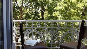 A balcony with ornate metal railings and two wooden chairs, one with a book on it. - Hotel Dom Sancho I (Lisbon)