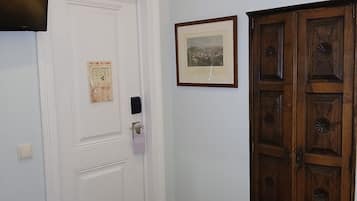 A room with a white door, a framed picture on the wall, a wooden wardrobe, and a red carpet.