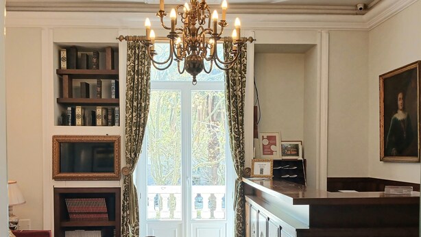 A room with a chandelier, bookshelves, a red sofa, ottomans, and a painting. - Hotel Dom Sancho I (Lisbon)