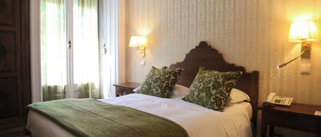 A hotel room with a large bed, two bedside lamps, a nightstand, and a telephone.