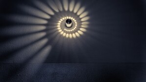 A circular light fixture casting a radial pattern of light on a dark surface.