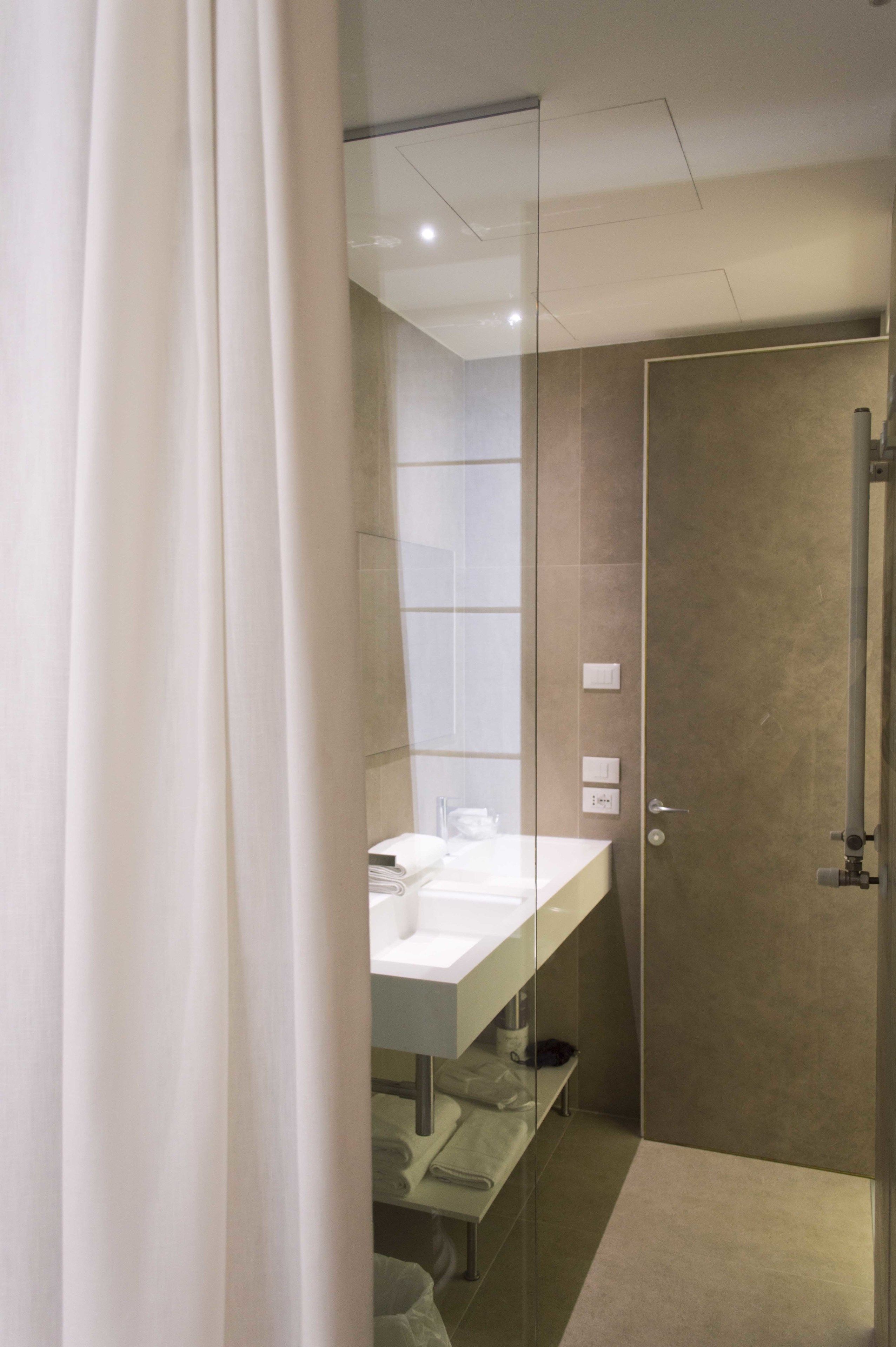 A modern bathroom with a glass shower enclosure, a white sink, and a towel rack.
