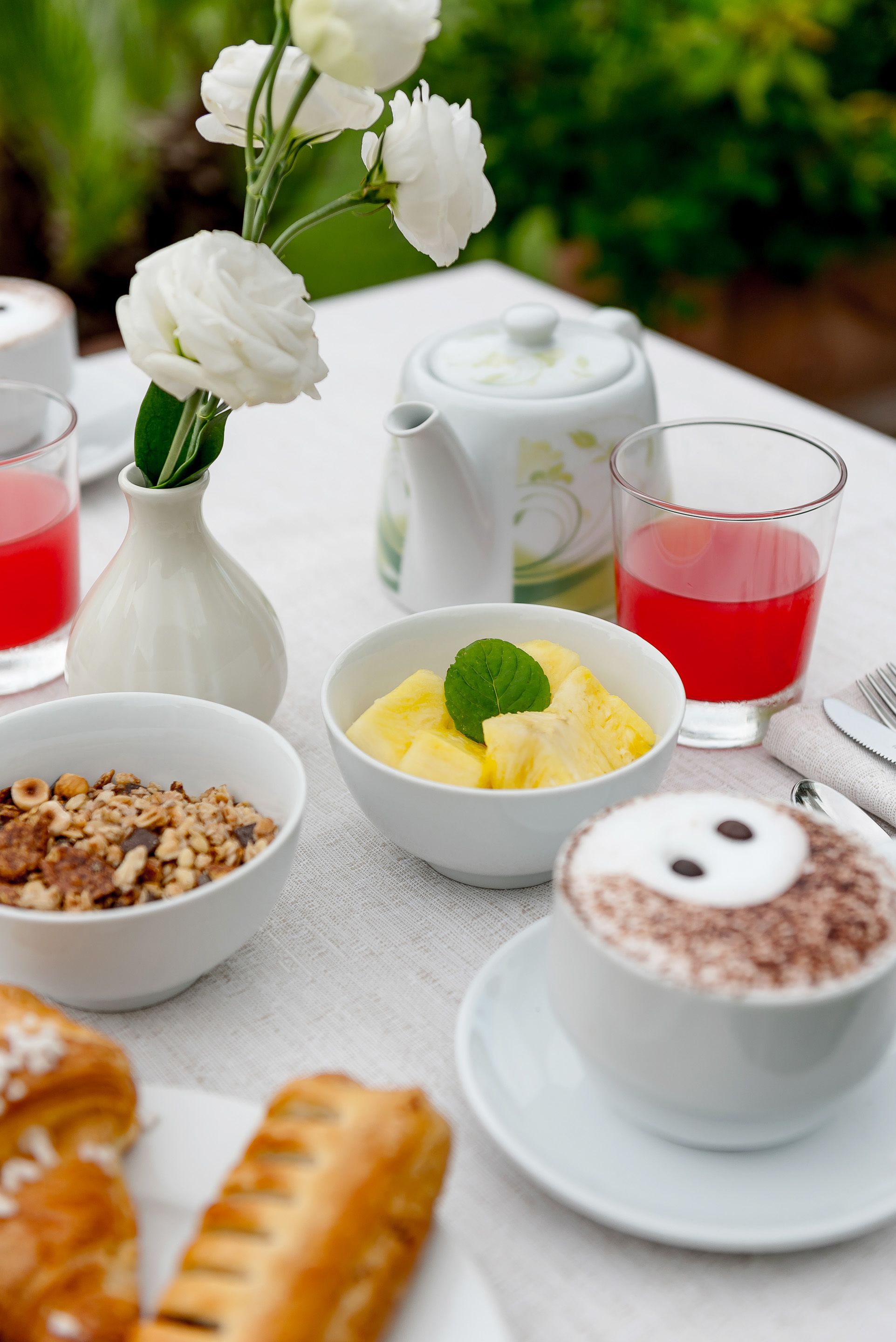 A table with breakfast items including a bowl of pineapple chunks, a pastry, and a cup of coffee.