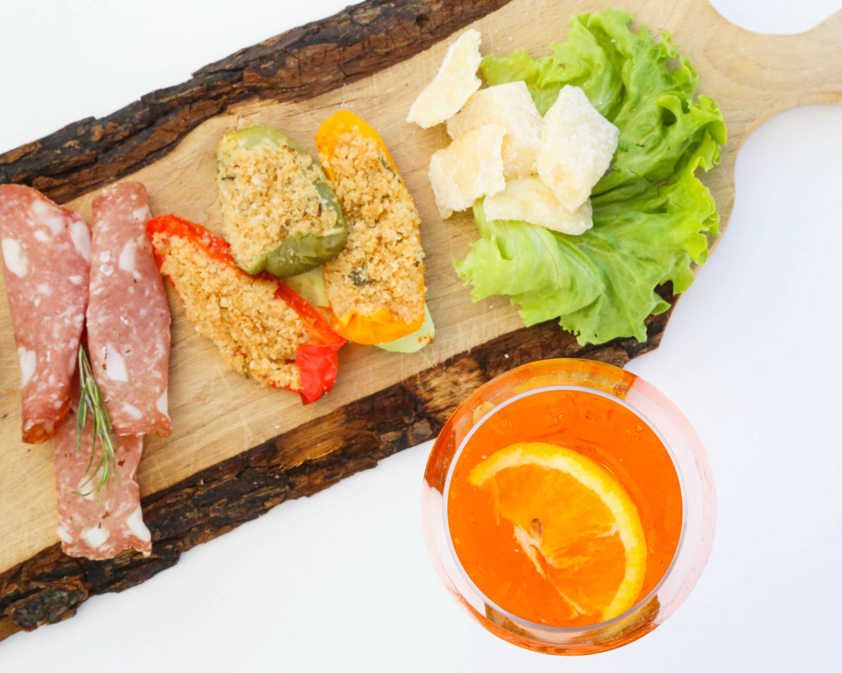 A wooden board with various food items and a glass of orange juice.