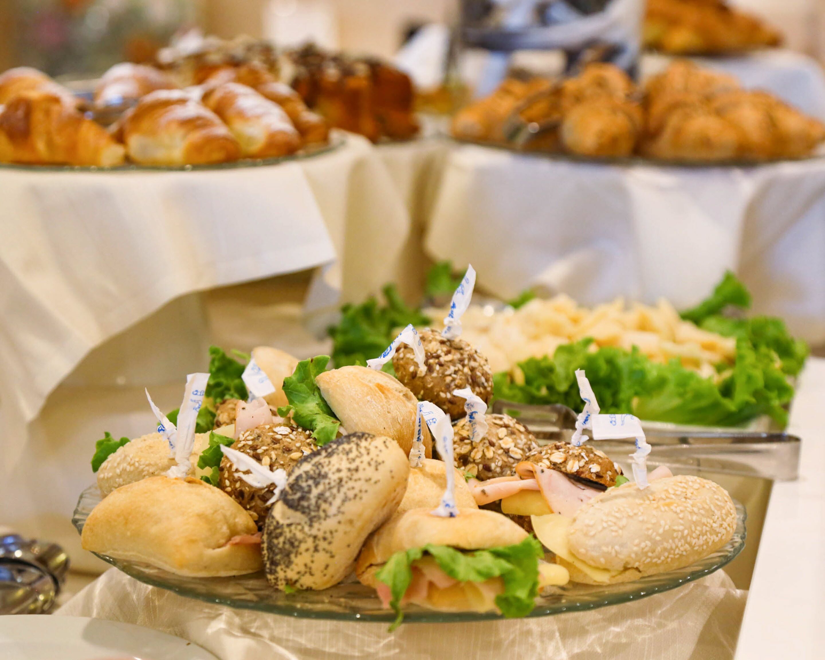 A buffet table with various sandwiches, croissants, and other baked goods.