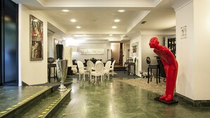 A spacious hallway with a dining area featuring a large table and chairs, a red sculpture, and artwork on the walls. - Hotel Delle Province (Rome)