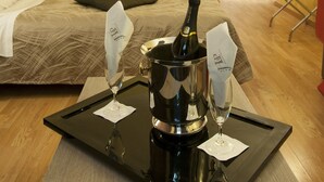 A hotel room with a bed, a bedside table with a bottle and glasses, a framed picture on the wall, and a wooden cabinet. - Hotel Delle Province (Rome)