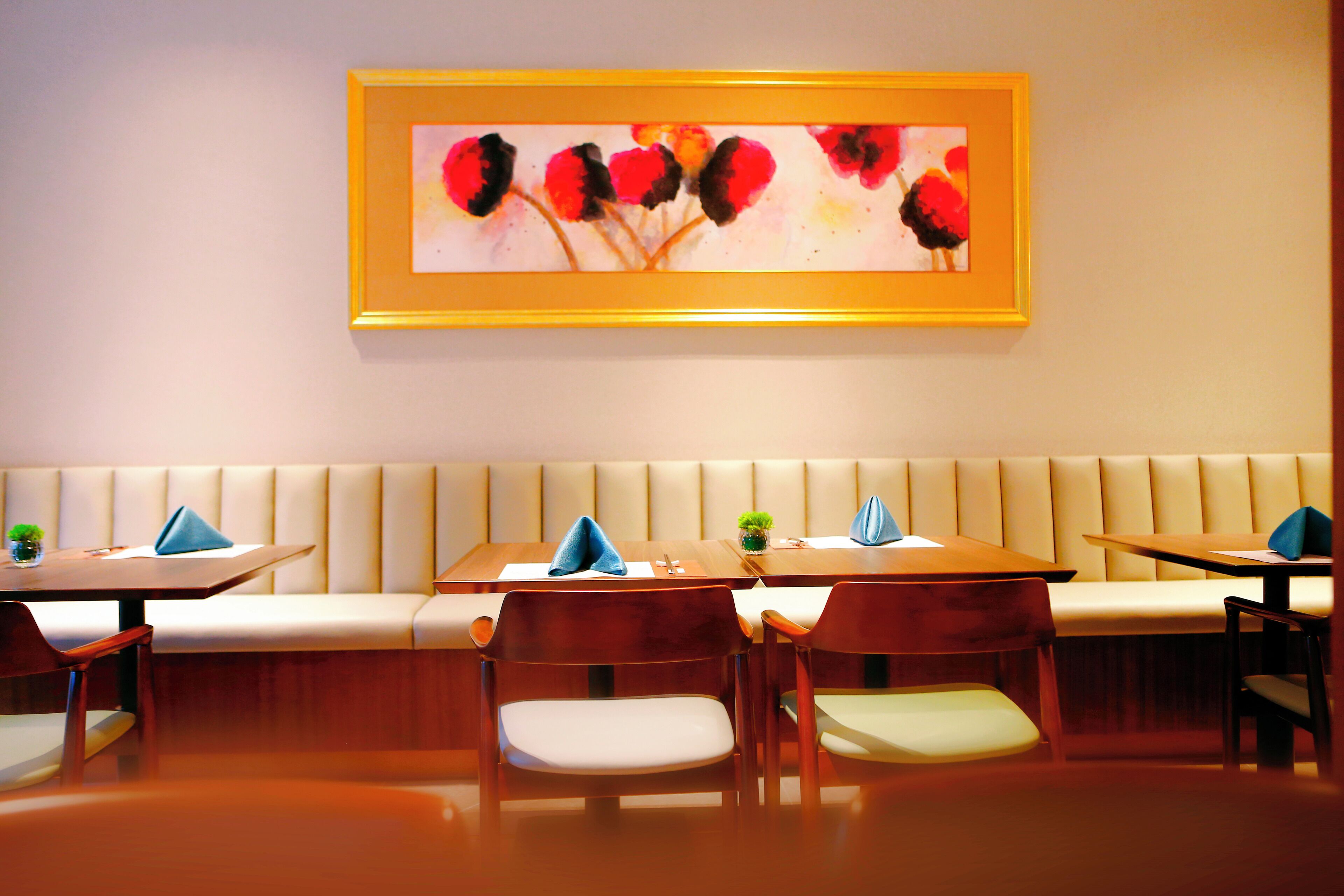 A restaurant with a long bench seating area, wooden tables, and chairs.