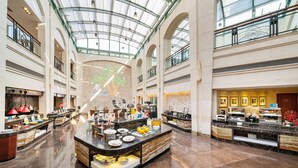 Een ruime atriumhal met een hoge plafond en een centraal gelegen eiland met etalages voor eten.