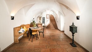 A cozy interior with a wooden bench, a table with chairs, a staircase, and a wall-mounted lantern. - Hotel die Hindenburg (Saalfelden am Steinernen Meer)