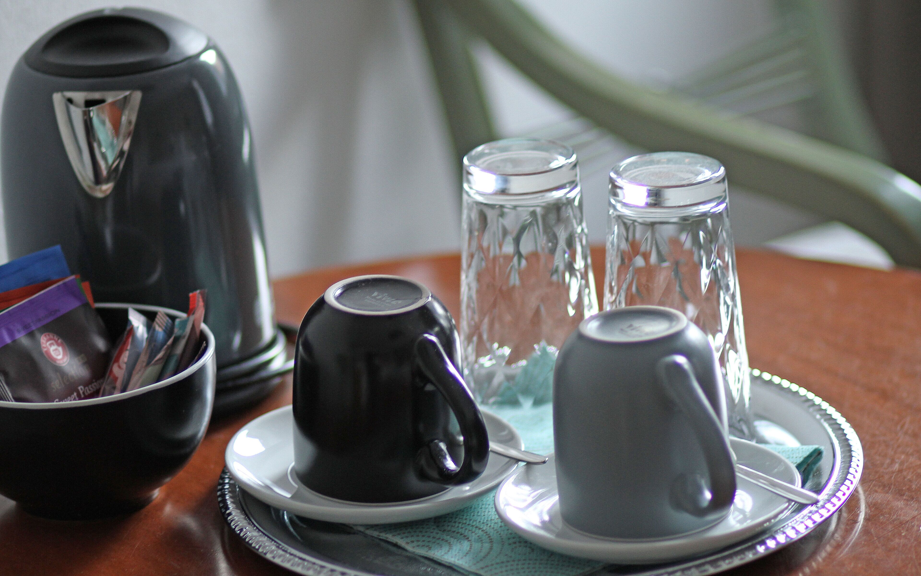 A table with a coffee maker, sugar cubes, and a glass pitcher.