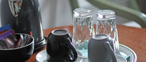 A table with a coffee maker, sugar cubes, and a glass pitcher.