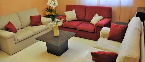 A living room with two sofas, a coffee table, and a vase with flowers.