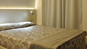 A bedroom with a bed, a headboard, a nightstand, a lamp, and a window with curtains. - Hotel Garibaldi (Mestre)
