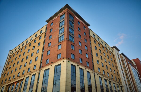 A multi-story hotel with a prominent corner entrance, large windows, and a clear sky.
