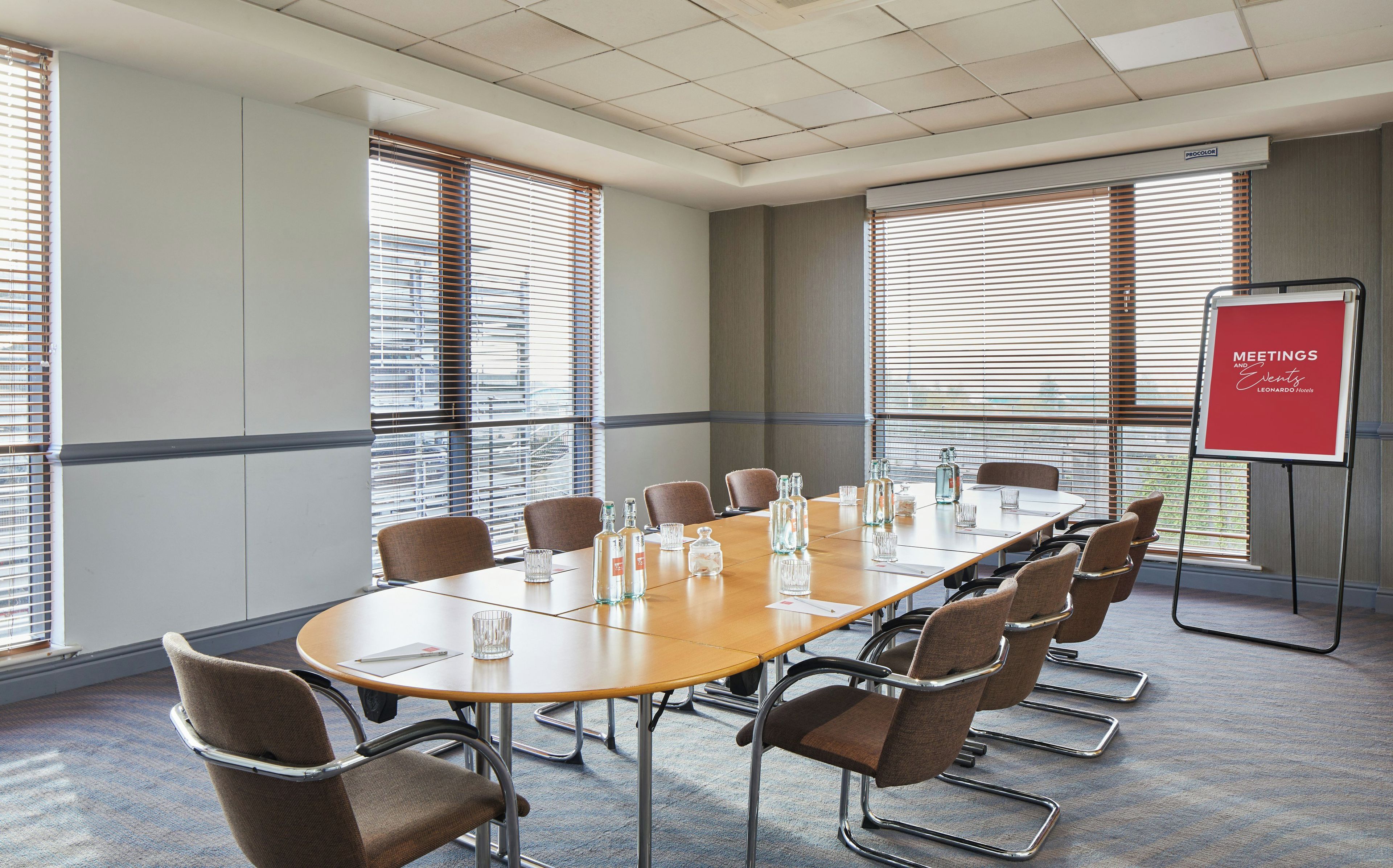 A conference room with a long table, chairs, and a red sign indicating it's for meetings and events.