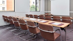 A conference room with a long table, multiple chairs, a projector screen, and large windows.