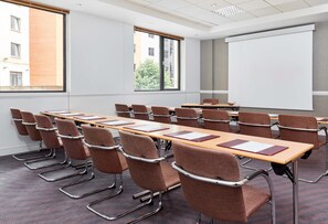 A conference room with a long table, multiple chairs, a projector screen, and large windows. - Leonardo Hotel Newcastle (Newcastle-upon-Tyne)