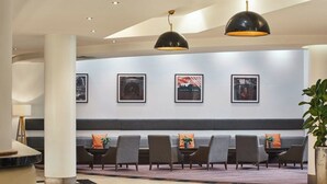 A lobby with a checkered floor, a seating area with chairs and a bench, and framed artwork on the wall.
