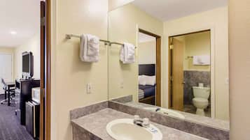 Une salle de bain d’hôtel avec un lavabo, un miroir et un porte-serviettes.