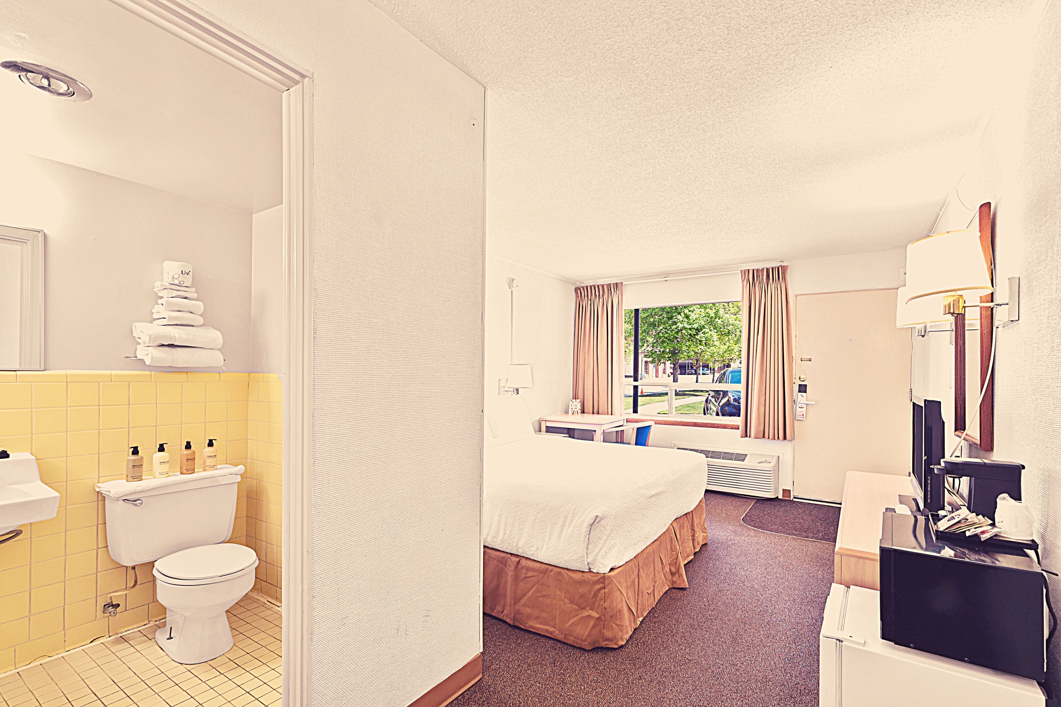 Une chambre d’hôtel équipée de toilettes, d’un lavabo, d’un lit et d’un bureau avec un ordinateur.