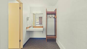 Um corredor com um banco de madeira, um espelho e um cabideiro.