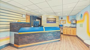 En reception med en blå disk, en skylt med texten ”Stardust Motel” och ett köksområde med träskåp.