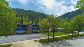 En byggnad med en blå och gul fasad, en parkeringsplats och en bergskedja i bakgrunden.
