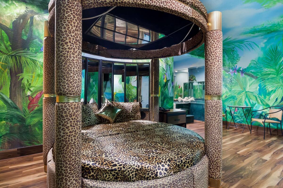 Une chambre dotée d’un lit rond, d’une décoration à motifs léopard et d’une grande fenêtre.