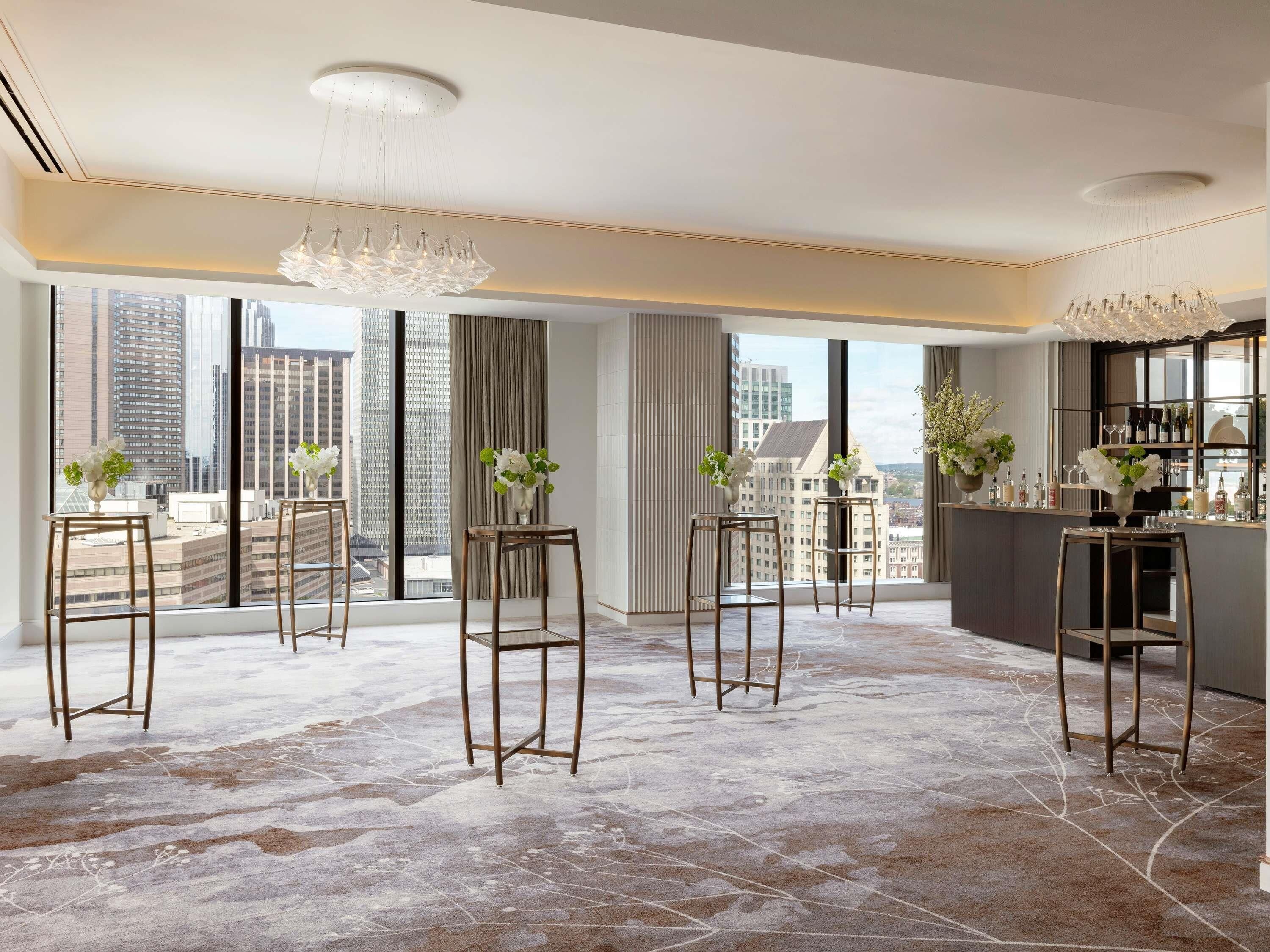 Een moderne hotelkamer met grote ramen, een barhoek en uitzicht over de stad.
