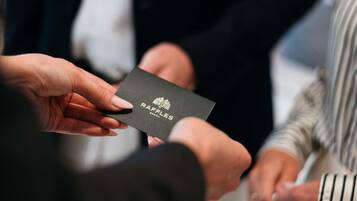 A person holding a black card with 'RAFFLES BOSTON' text.