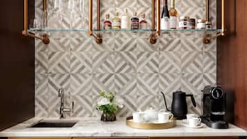 A kitchen with a marble countertop, a coffee machine, a tea set, and a wine rack with bottles.