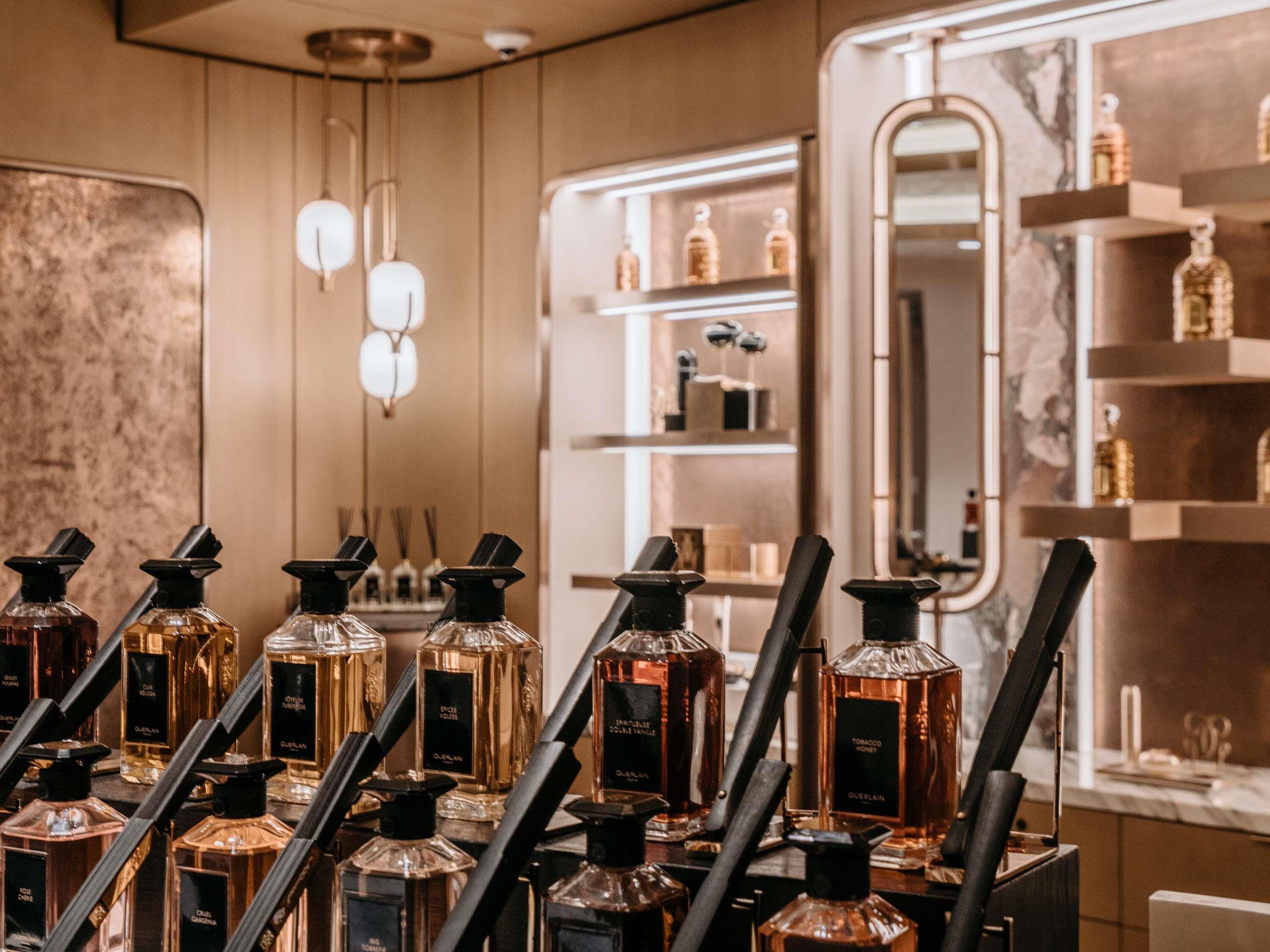 A display of perfume bottles in a store with wooden paneling and a mirror.