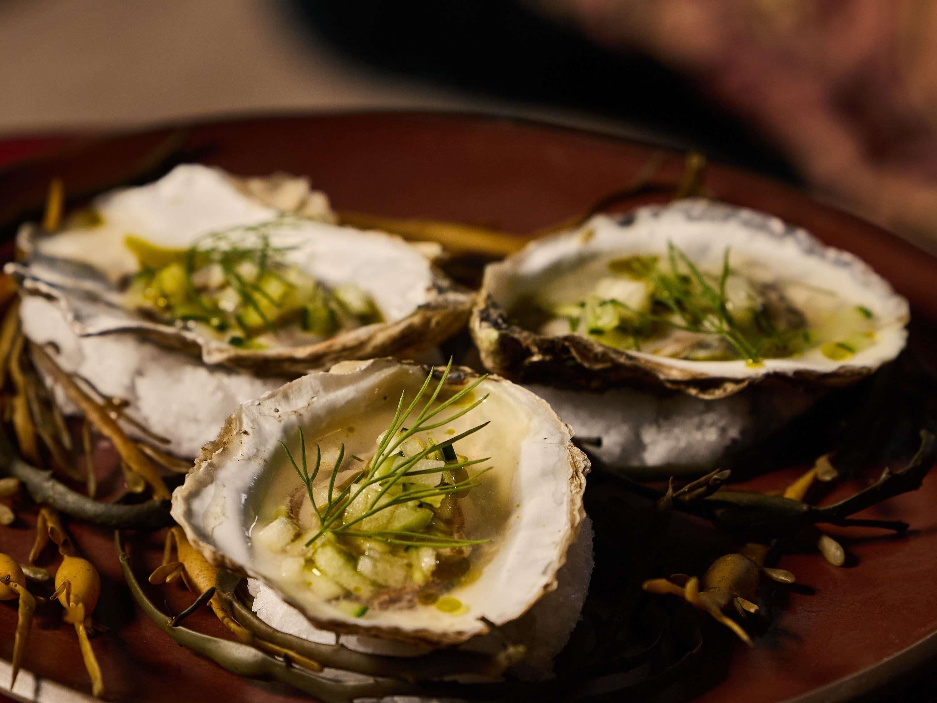Tres ostras en un plato con guarnición.