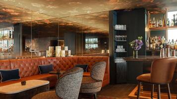 A bar area with a leather booth, bar stools, and a bar stocked with bottles.