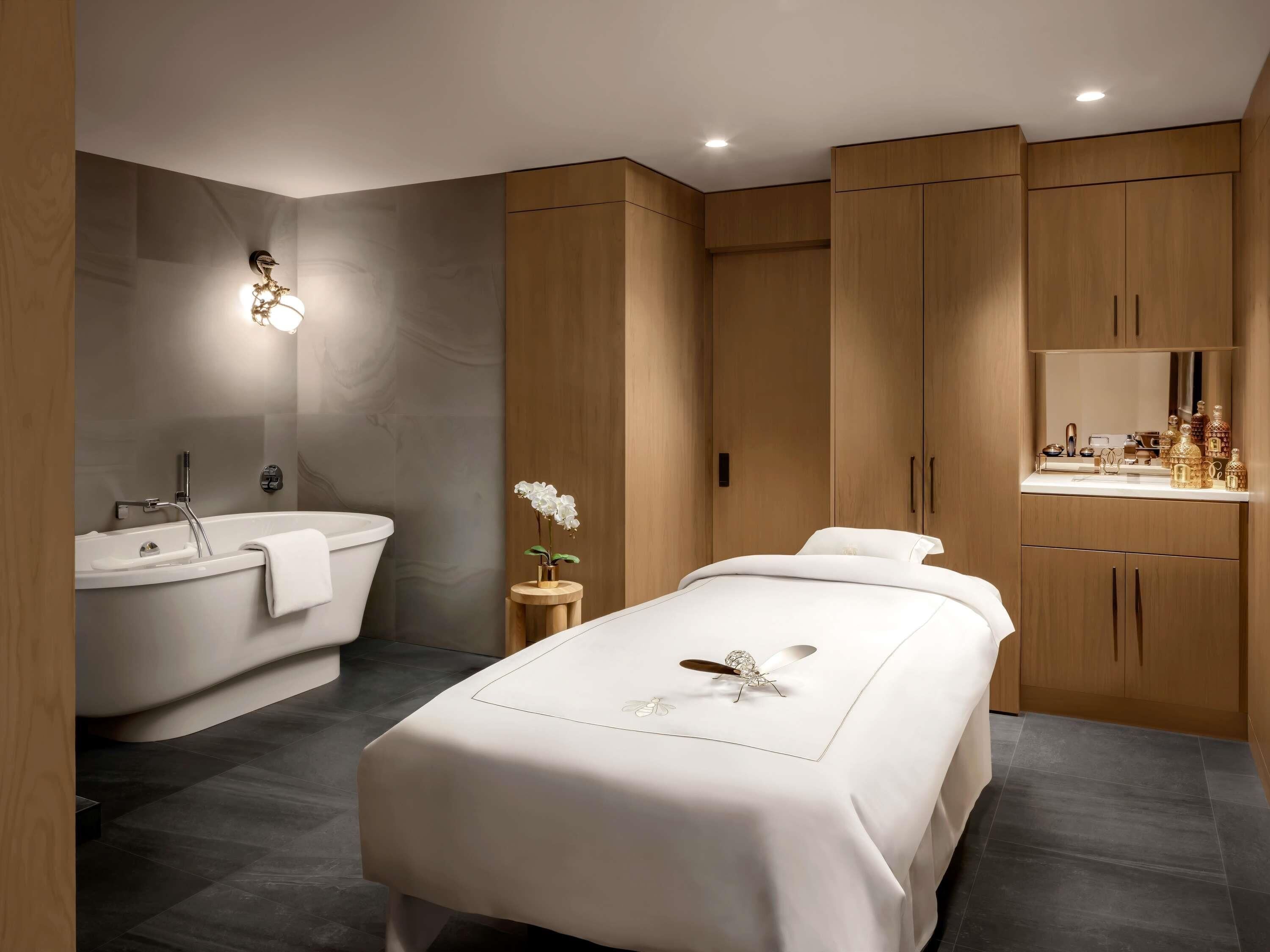 Un dormitorio moderno con cama, tocador con espejo y bañera.